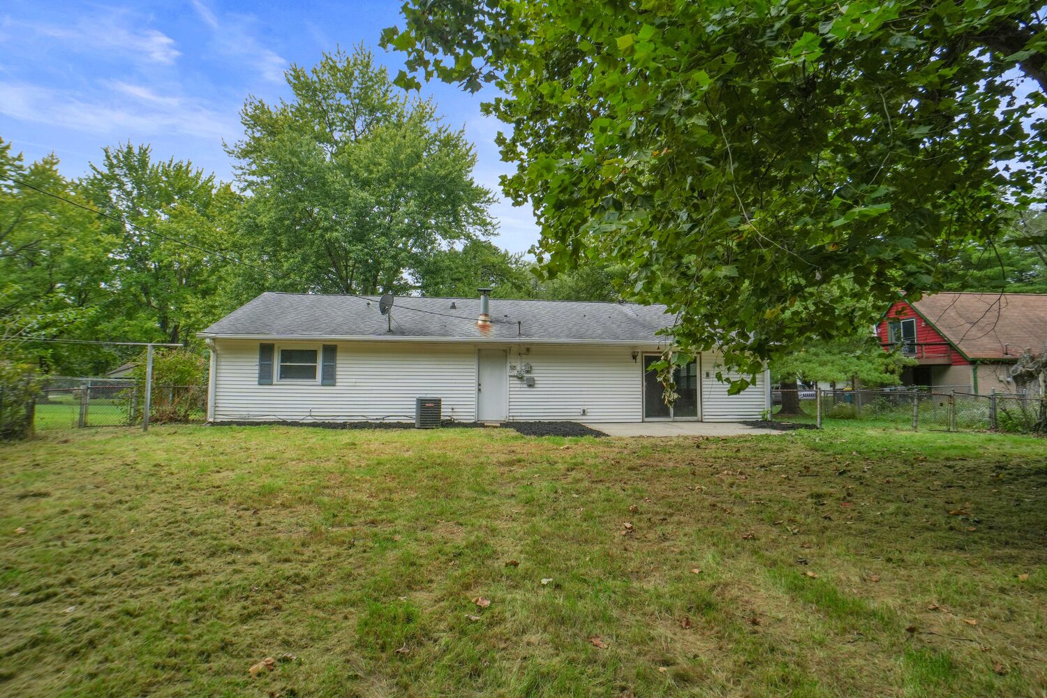 Rear of the home and fully fenced backyard under mature trees